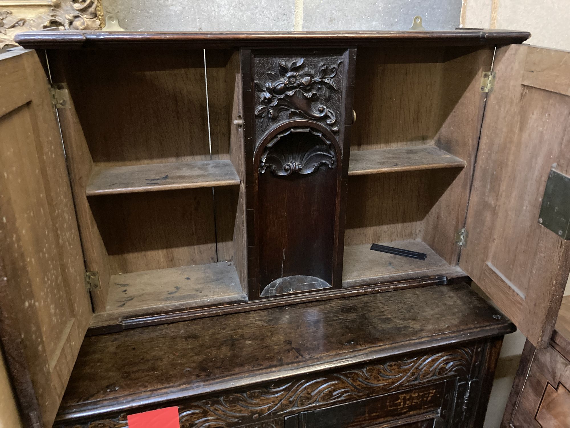 An 18th century style carved oak two door wall cabinet, with concealed central compartment, width 80cm, depth 19cm, height 50cm